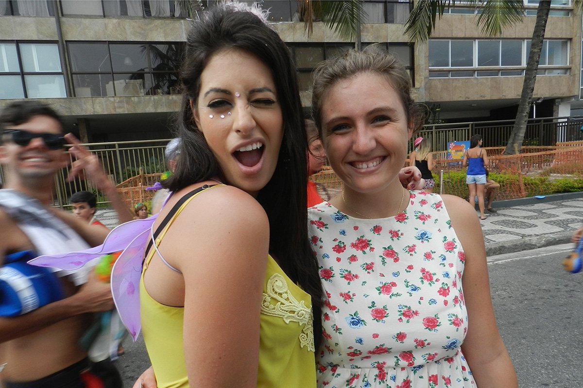 Two lovely girls enjoying street festivities in Ipanema. One of them is winking at the camera.